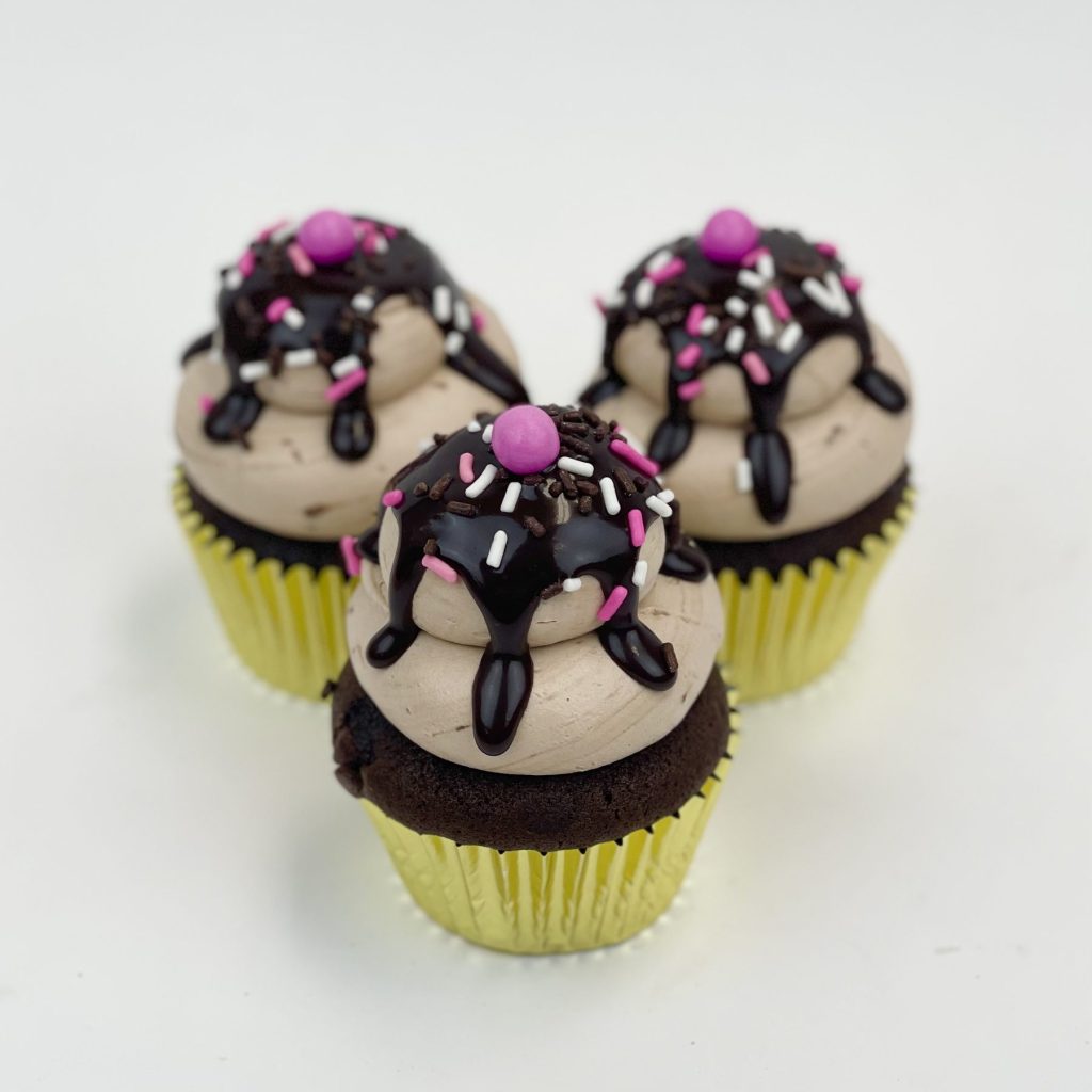 Chocolate cupcakes with pink drizzle and candy decorations