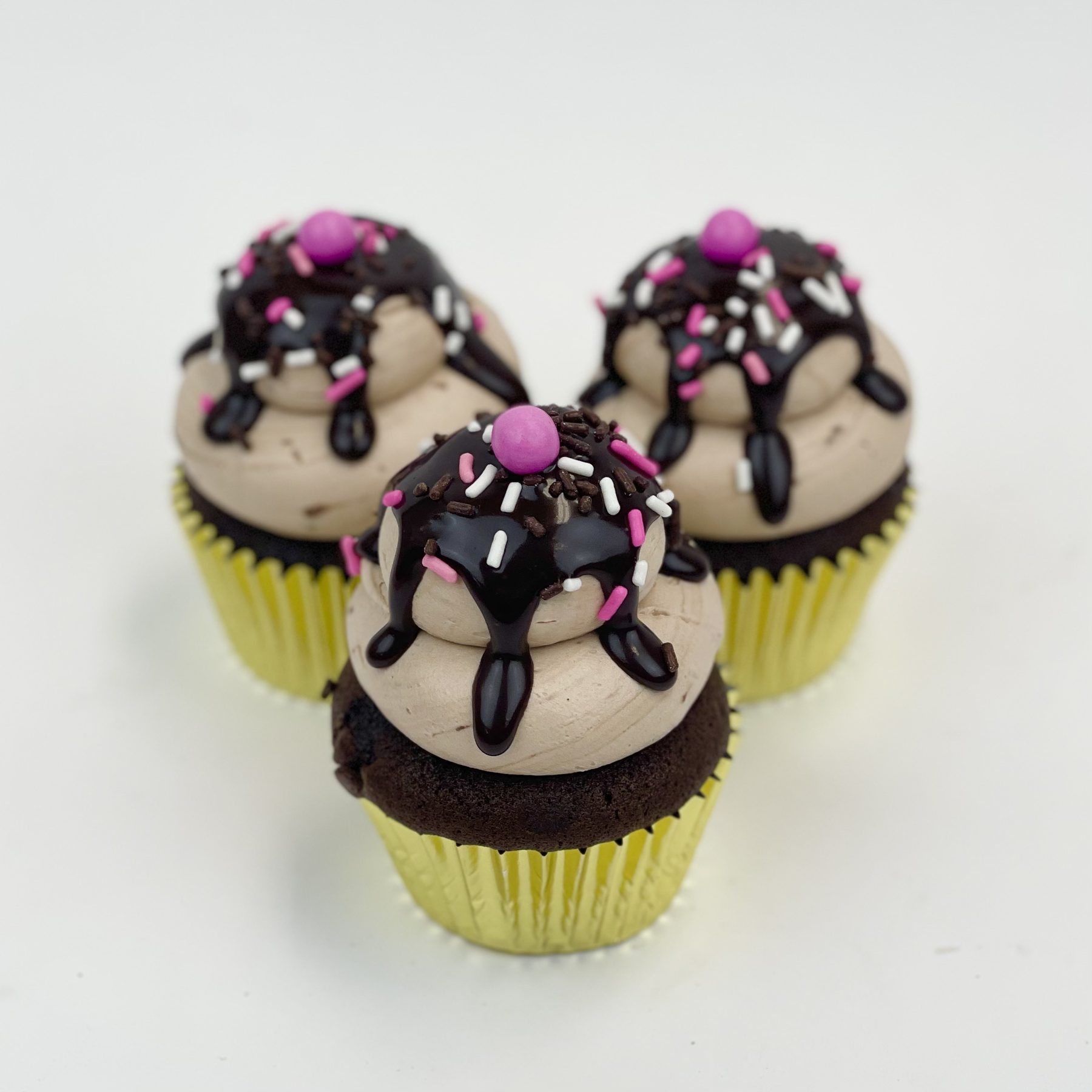 Chocolate cupcakes with pink drizzle and candy decorations