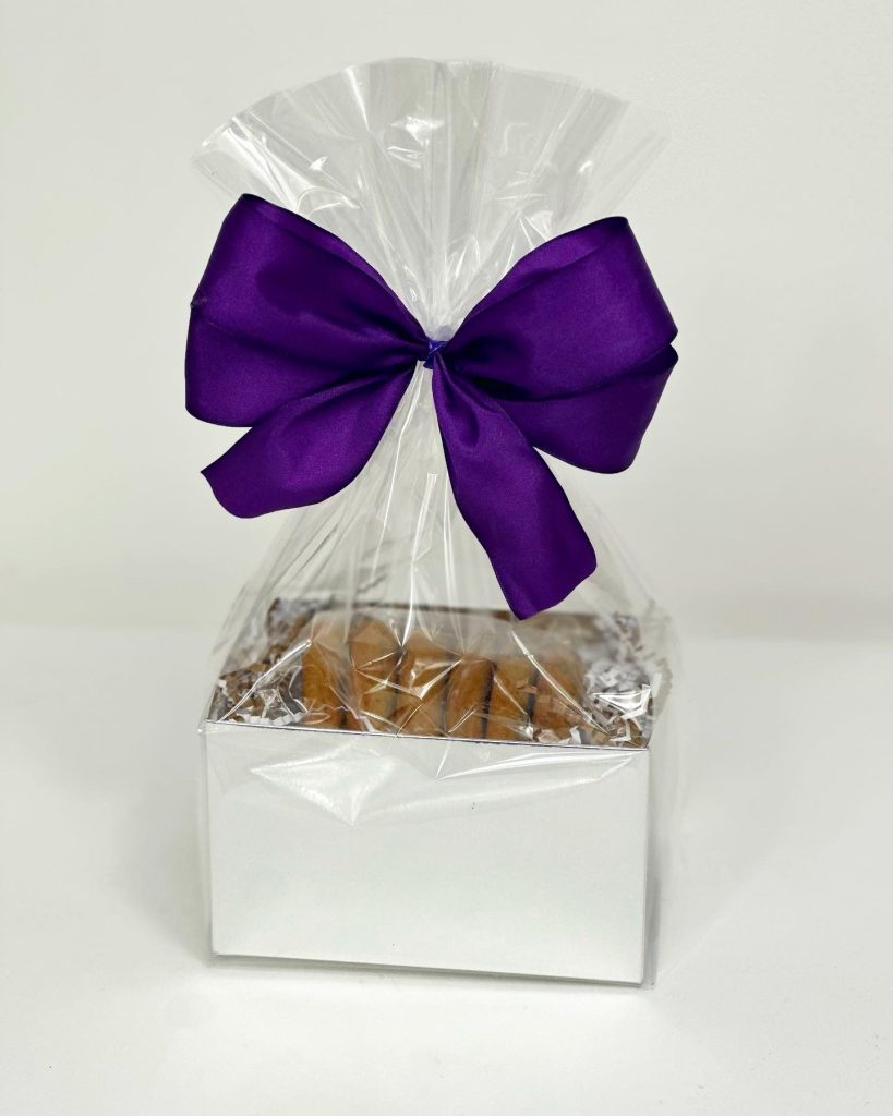 A white gift box finished with a purple cellophane bow