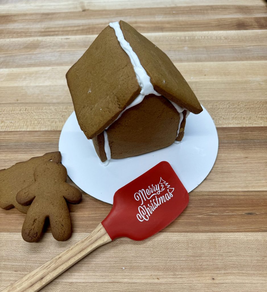 A gingerbread house beside a gingerbread man and a festive spatula