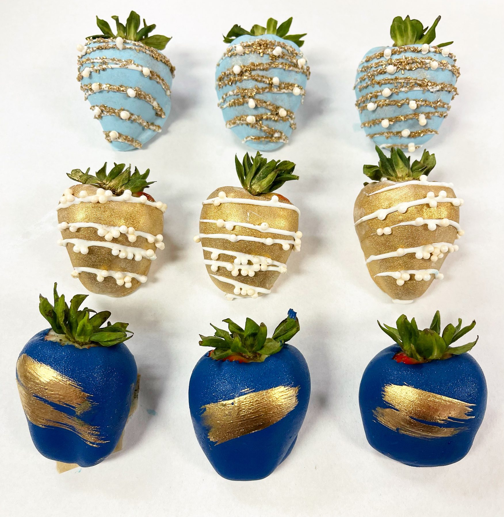 Chocolate-dipped strawberries decorated in navy, gold and white