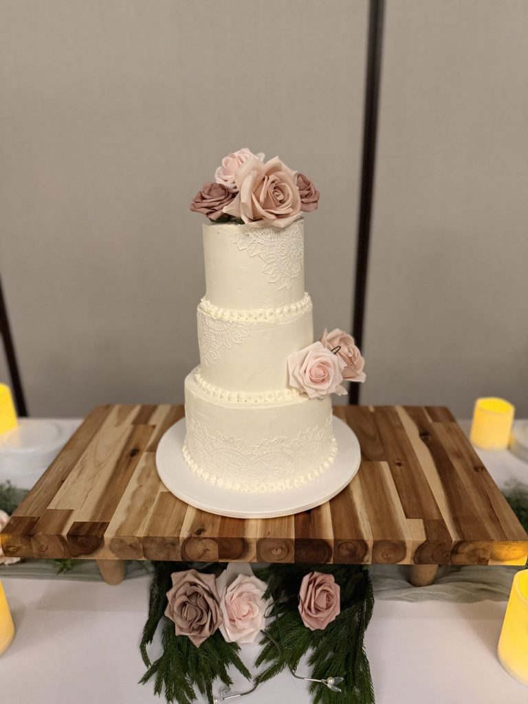 A four-tier white wedding cake decorated with sugar roses