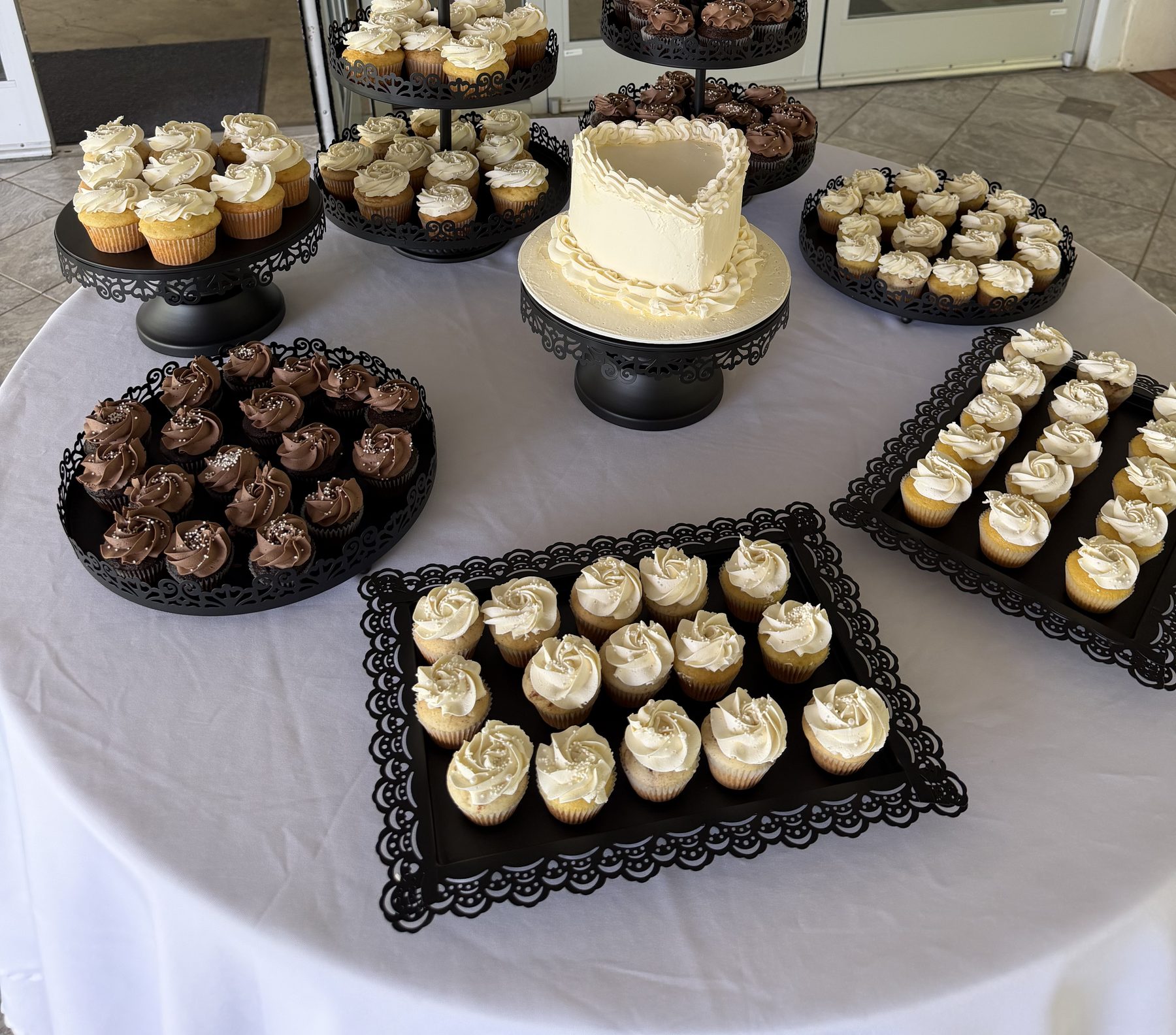 A styled event dessert table of cupcakes and a cutting cake
